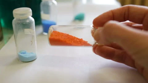 Potassium dichromate crystals (K2Cr2O7) in a container holds a woman's hand. Clo Stock Footage 85612689