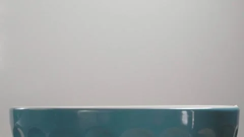 Potato chip falling into blue bowl against light background during food Stock Footage 343968530
