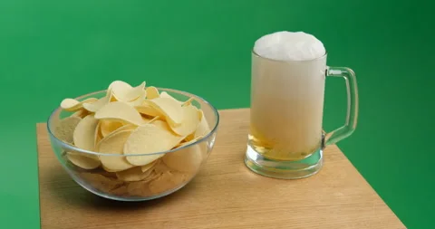 Potato chips and beer is poured into a glass Stock Footage 154085239
