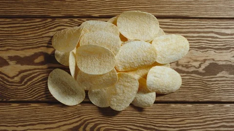Potato chips appear one by one on wooden surface. Stop motion animation Stock Footage 129648143