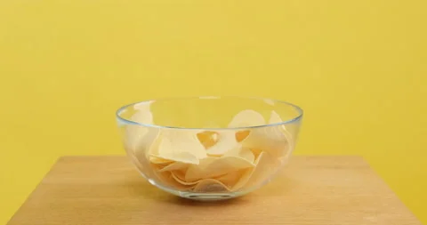 Potato chips appear one by one on plate Stockbeeldmateriaal 154043519
