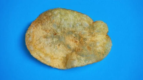 Potato chips on a blue background. Crispy potato slices close up, top view Stock Footage 208673625