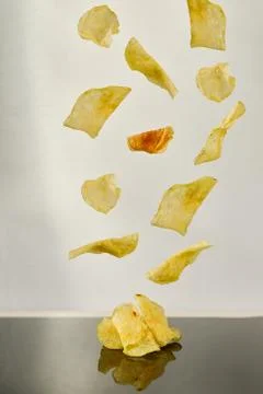 Potato chips falling white background and black reflection Stock Photos