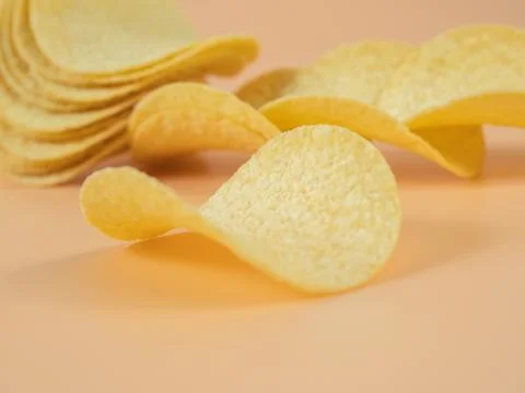 Potato chips on an orange background. Close-up. Stock Photos