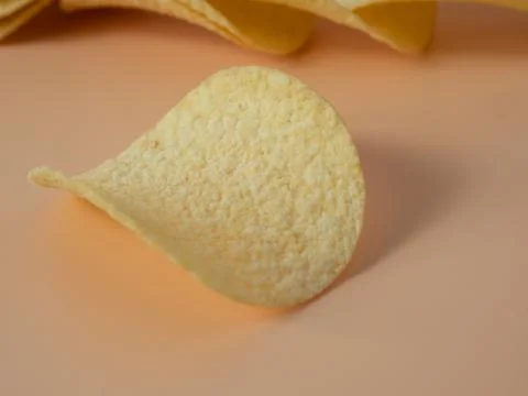 Potato chips on an orange background. Close-up. Stock Photos