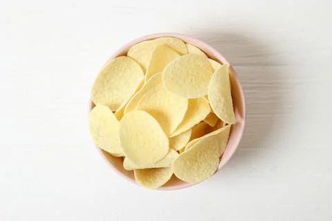Potato chips in a plate on a colored background top view. Stock Photos