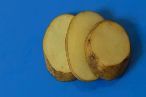 Potato cut slice pieces closeup shot on isolated blue background Stock Photos