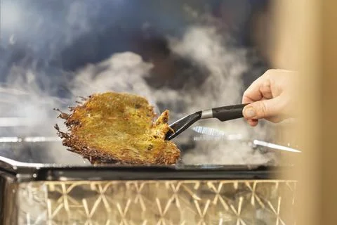 A potato pancake that pulls a hand out of the pan Stock Photos