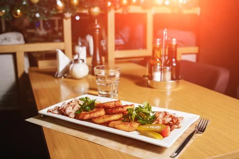 Potato pancakes with bacon on a white rectangular plate on a table in a resta Stock Photos