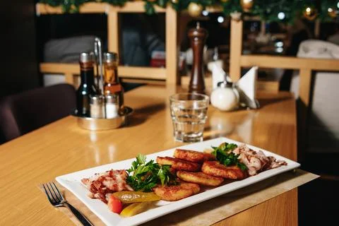 Potato pancakes with bacon on a white rectangular plate on a table in a resta Stock Photos