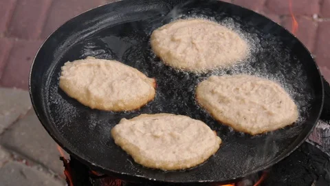 Potato pancakes, fried deep-fried in a pan over an open fire. Stock-Footage 100881446