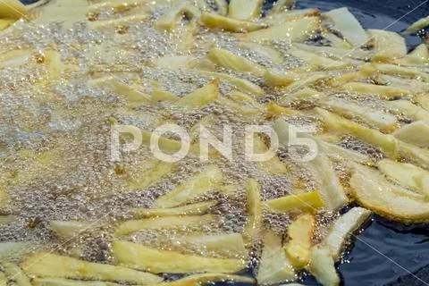 Potato pieces are fried in a large, hot frying pan, in boiling oil Stock Photos