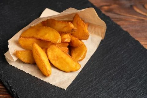 Potato rustic tableware slate, black stone on a wooden background. Stock Photos