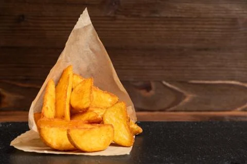 Potato rustic tableware slate, black stone on a wooden background. Close up. Stock Photos