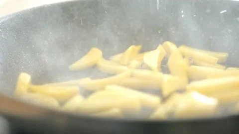 Potato slices fall into a frying pan with sunflower oil close-up Stock Footage 236094036