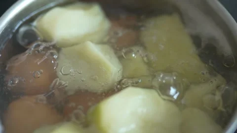 Potatoes and eggs boiling in a pot of bubbling water Stock Footage 333634691