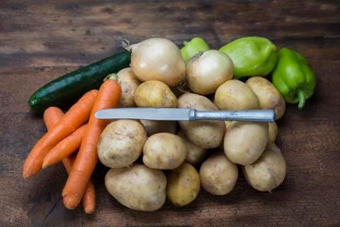Potatoes and vegetable on the rustic table with knife Stock Photos