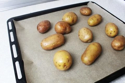Potatoes are baked on a baking sheet in the oven 库存照片