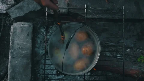 Potatoes are Cooked in a Large Cauldron Over an Open Fire During the Day Stock Footage 246474531