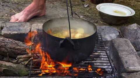 Potatoes are Cooked in a Large Cauldron Over an Open Fire During the Day Stock Footage 250240304