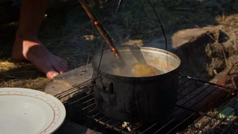 Potatoes are Cooked in a Large Cauldron Over an Open Fire During the Day Stock Footage 250240449