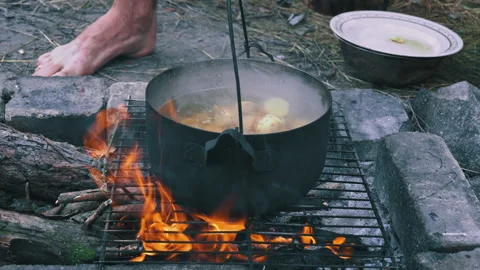 Potatoes are Cooked in a Large Cauldron Over an Open Fire During the Day Stock Footage 250240640
