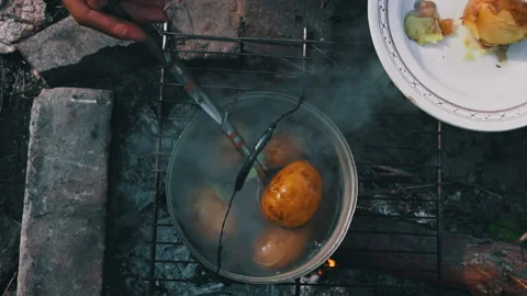 Potatoes are Cooked in a Large Cauldron Over an Open Fire During the Day Stock Footage 252202287