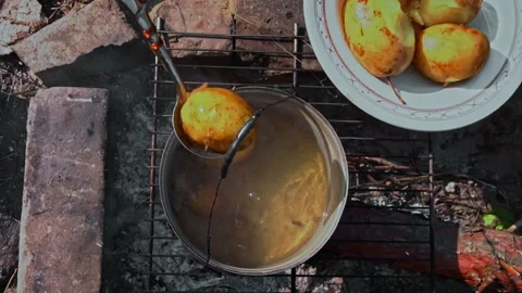 Potatoes are Cooked in a Large Cauldron Over an Open Fire During the Day Stock Footage 252805381