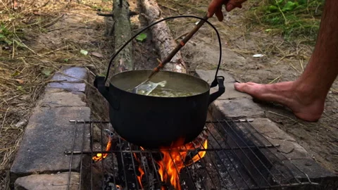 Potatoes are Cooked in a Large Cauldron Over an Open Fire During the Day Stock Footage 252807104