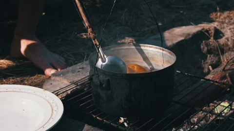 Potatoes are Cooked in a Large Cauldron Over an Open Fire During the Day Stock Footage 252807300