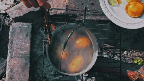 Potatoes are Cooked in a Large Cauldron Over an Open Fire During the Day Stock Footage 252807598