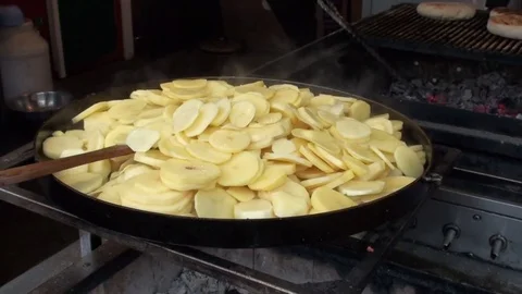 The potatoes are fried in a large frying pan on the grill. Stock Footage 76486322