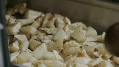 Potatoes being stirred in  a tray out of the oven - slow motion Stock Footage 129016276