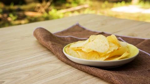 Potatoes chips on a wooden table. Stock Photos