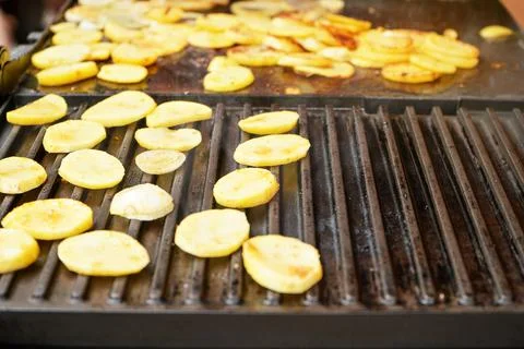 Potatoes cut into small chips grilled on electric grill, closeup detail Stock Photos