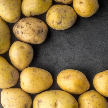 Potatoes on the dark stone table square Stock Photos
