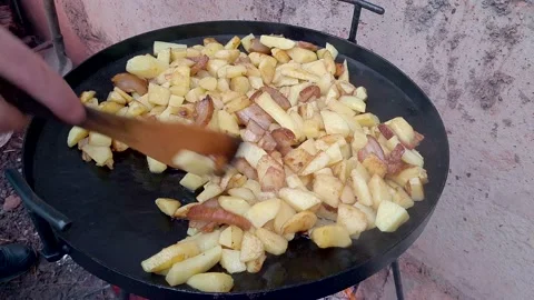 Potatoes fried in a fat on huge black round pan made of cultivators disc Stock Footage 148272002
