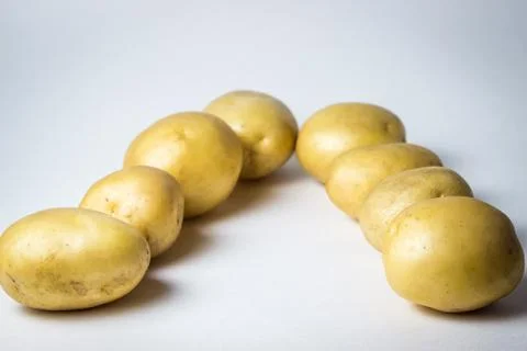 The potatoes lie in two rows on a white background. Stock Photos