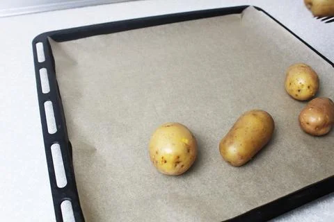 Potatoes lying on a baking sheet side view Stock Photos
