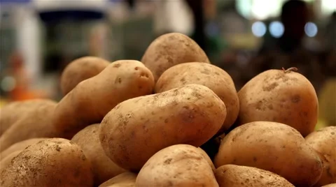 Potatoes on stall, close up, people passing to market place in background. 4k Stock Footage 54366489