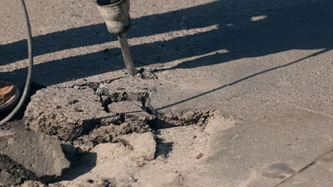 Pothole road repair. A worker is using a jackhammer to break up asphalt within Stock Footage 256713928