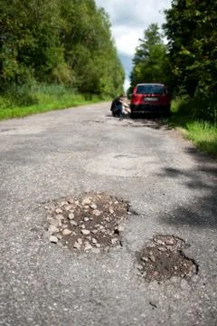 Potholes and rubbles in damaged woods road Stock Photos