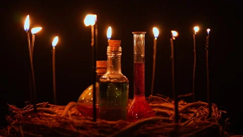 Potion vials surrounded with black magic candles and forest twigs on black .. Stock Footage 345451031