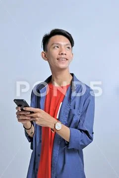 Potrait of handsome young asian man holding a smart phone and wear wristwatch Stock Photos