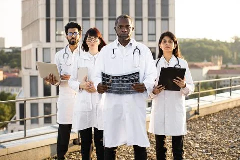 Potrait of medical workers using gadgets while examining results of x ray scan. Stock Photos
