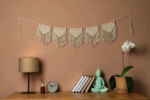 Potted orchid, decor elements and books on wooden table near brown wall with  Stock Photos