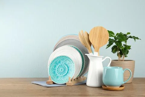 Potted plant and set of kitchenware on wooden table near light wall, space fo Stock Photos