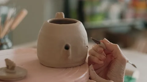 Potter applies a pattern to a clay teapot in a ceramic workshop, close-up. The Stock Footage 153095020