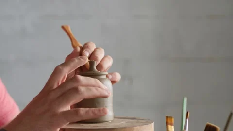 A potter attaches a handle to the lid of a clay teapot on a potter's wheel Vídeos de archivo 145543816