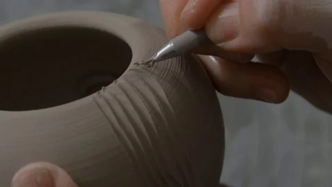The Potter begins forming a pattern on a clay vase. The first cut on the vase Stock Footage 128455850